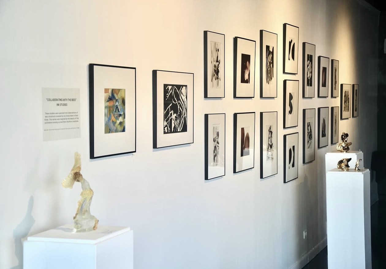 Salon-style arrangement of framed artworks and sculptures on white plinths