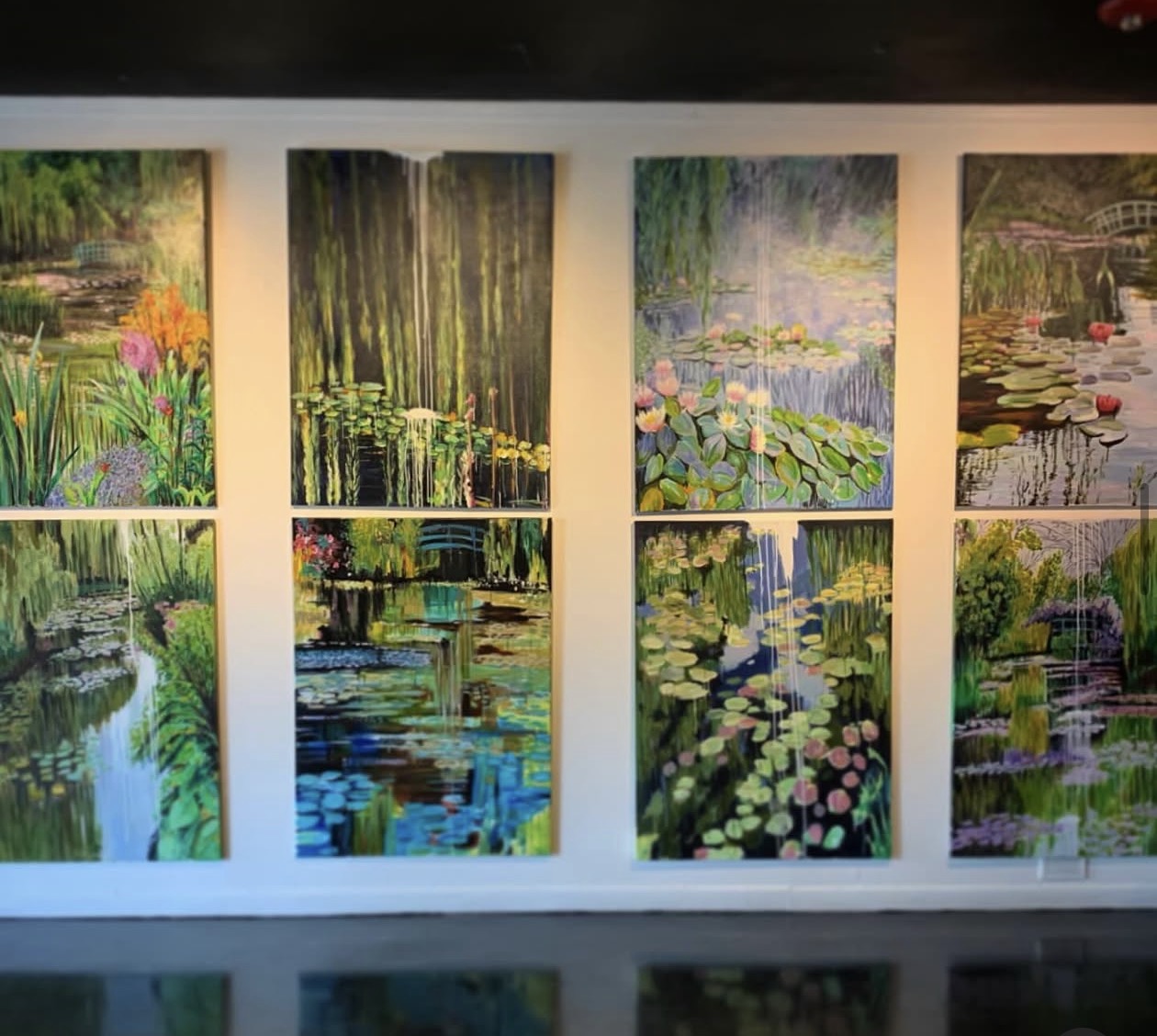 Eight colorful water-lily paintings arranged on a wall at The Gallery
